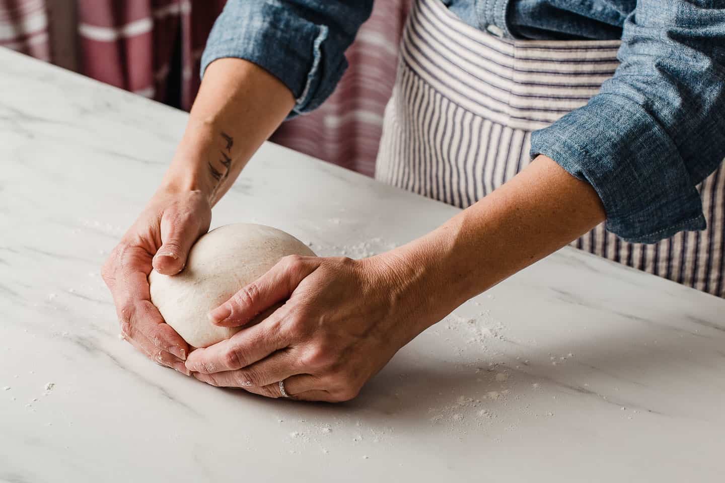 A woman shaping a loaf of sourdough.