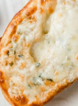A closeup photograph of cheesy garlic bread.