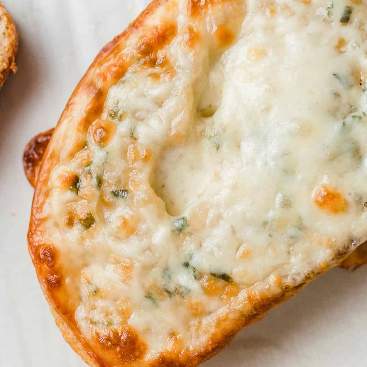 A closeup photograph of cheesy garlic bread.