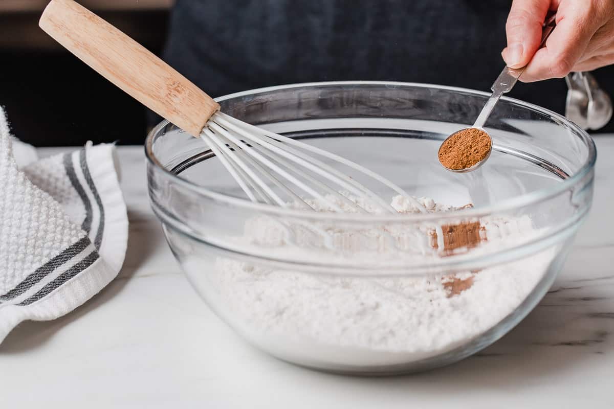 A woman mixing dry ingredients in a mixing bowl.