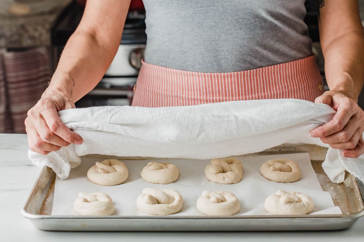 A woman covering pretzel dough with a towel.
