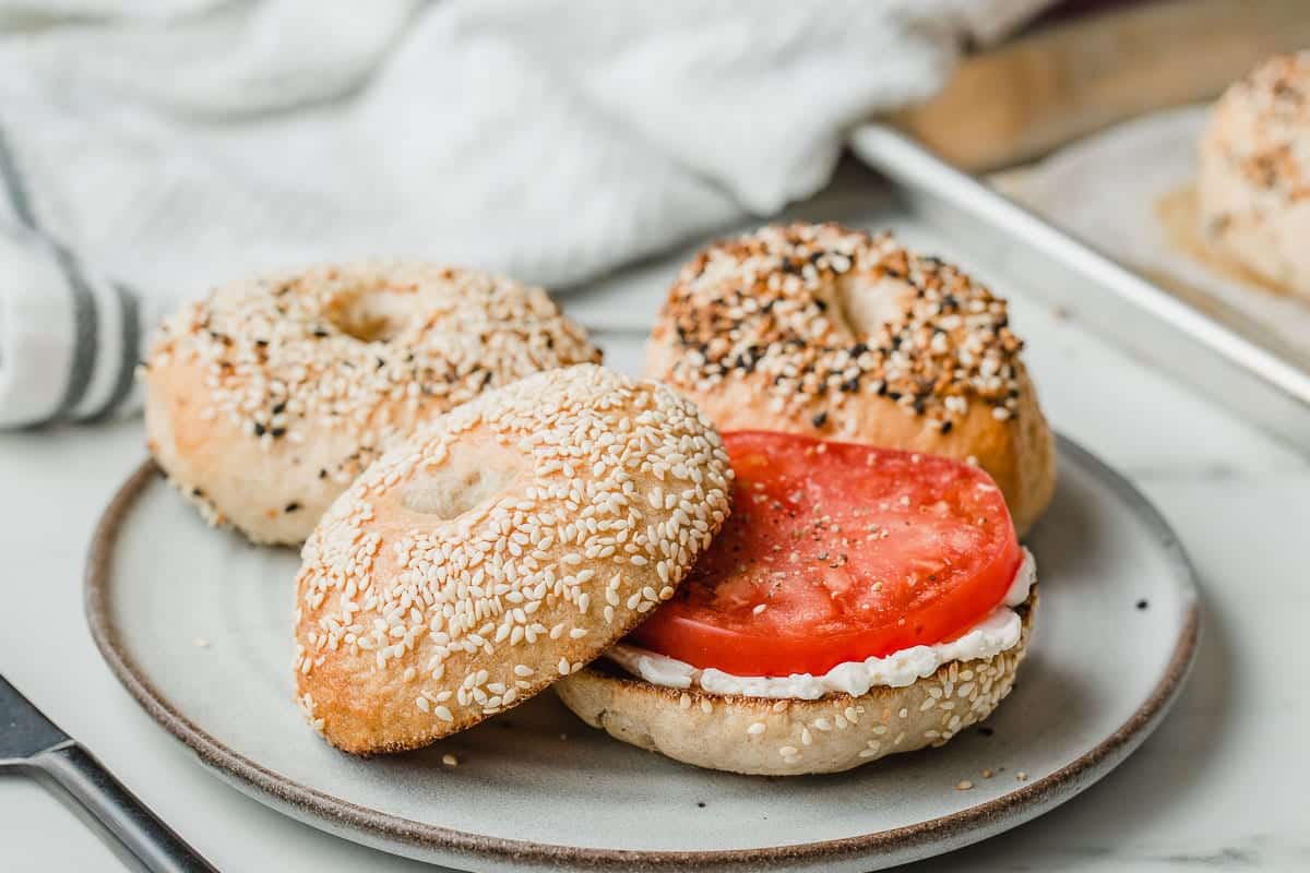 A sourdough bagel toasted with cream cheese and a slice of tomato.