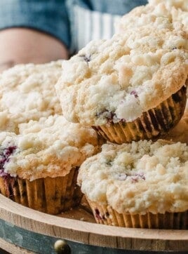 A woman holding a tray of sourdough blueberry muffins.
