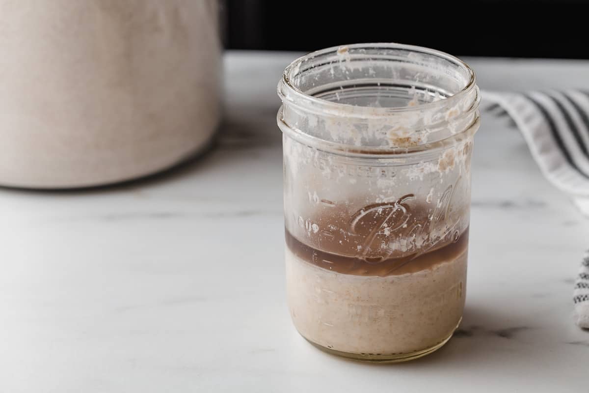A jar of sourdough starter with a layer of hooch on top.