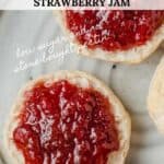 A closeup picture of strawberry jam on a biscuit.