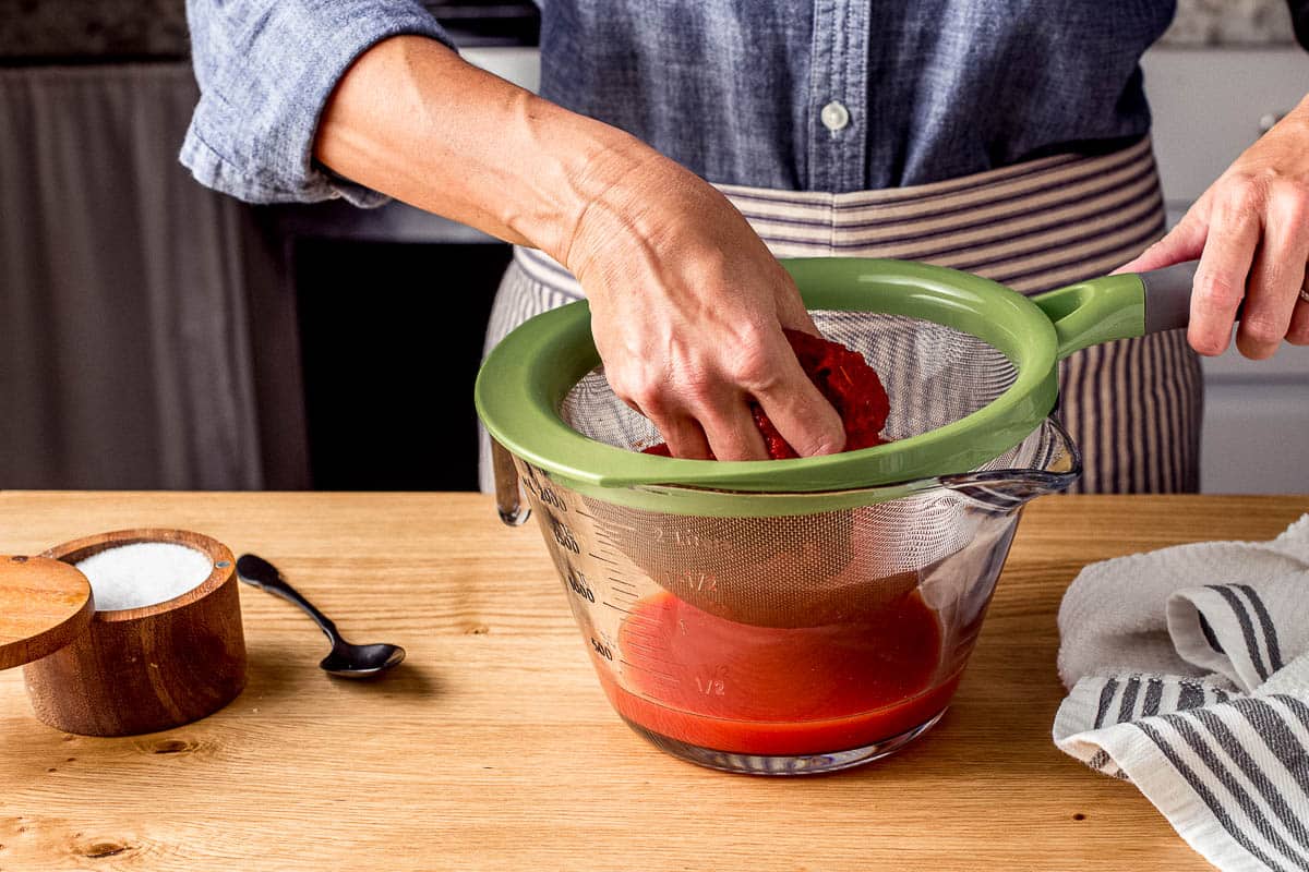A woman crushing tomatoes for pizza sauce.