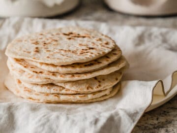 Sourdough tortillas stacked on a plate.