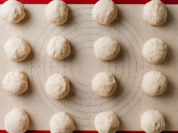 Sourdough tortilla dough balls resting on a silicone mat.