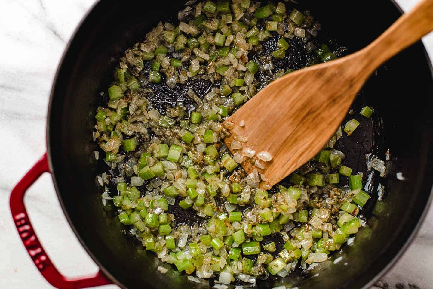 Diced celery and onions cooking in a pot.