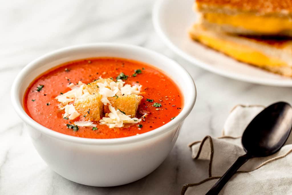 Homemade tomato soup in a bowl with cheese and croutons.