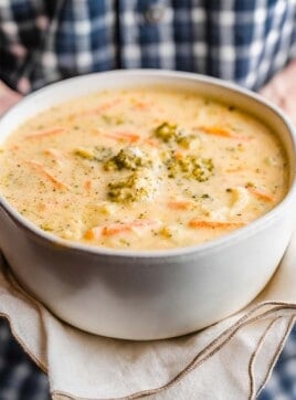 A woman holding a bowl of homemade broccoli cheese soup.