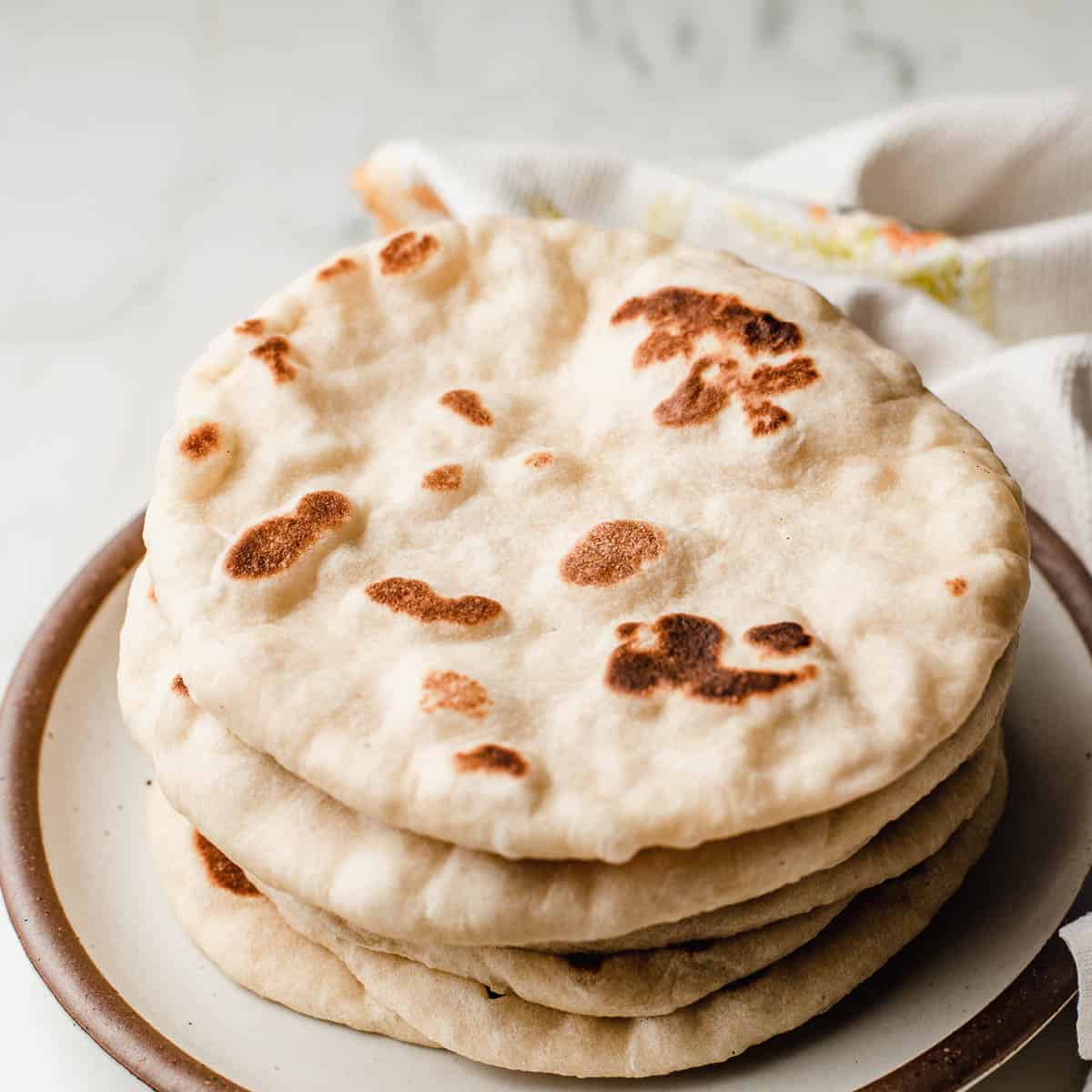 Sourdough naan stacked on a plate.