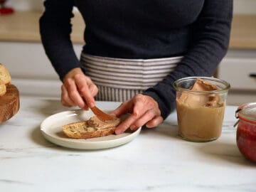A person spreading almond butter onto toast.