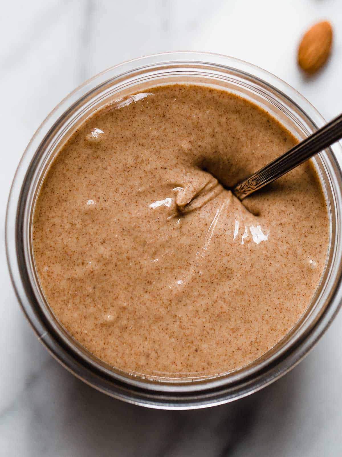 Homemade almond butter in a weck jar with a spoon.