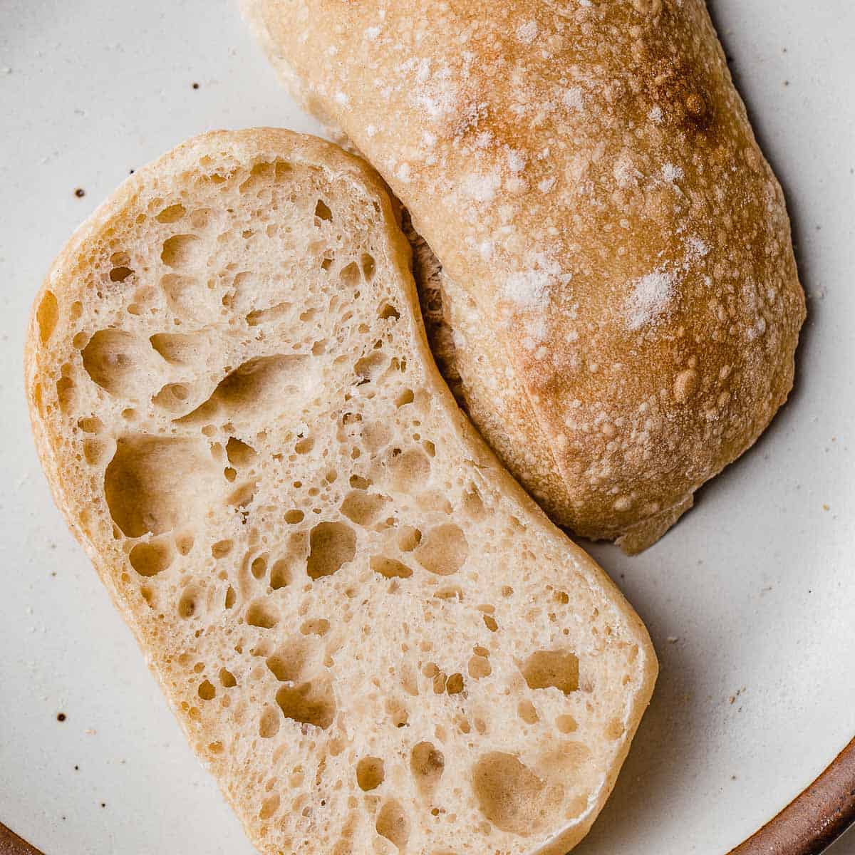 Sourdough ciabatta bread sliced in half on a plate.