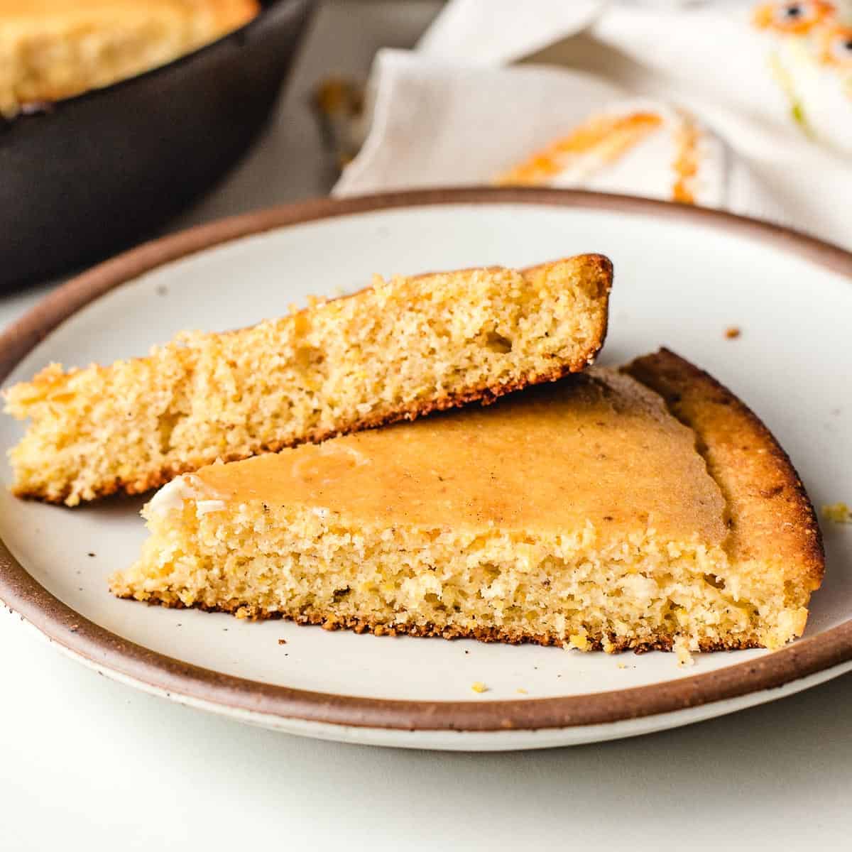 Two slices of cornbread on a plate.