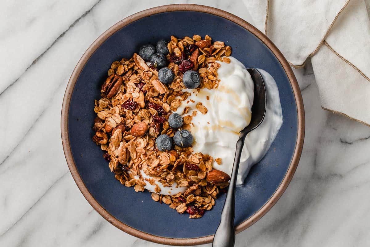 Granola in a blue bowl with blueberries and yogurt.