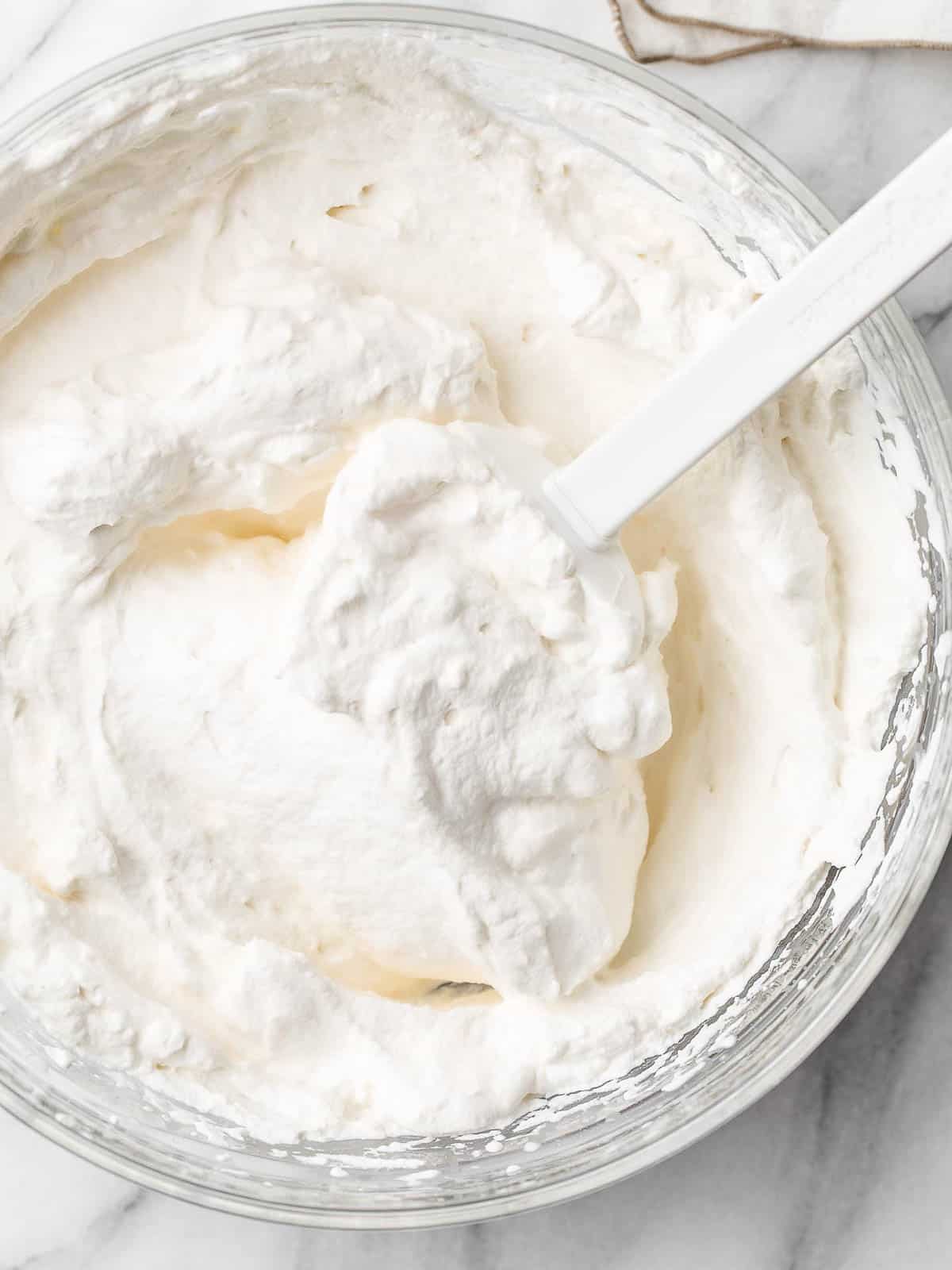 Top view of homemade whipped cream in a mixing bowl.