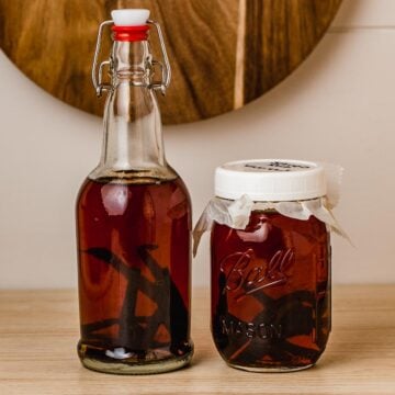 Two jars of homemade vanilla extract on a counter.