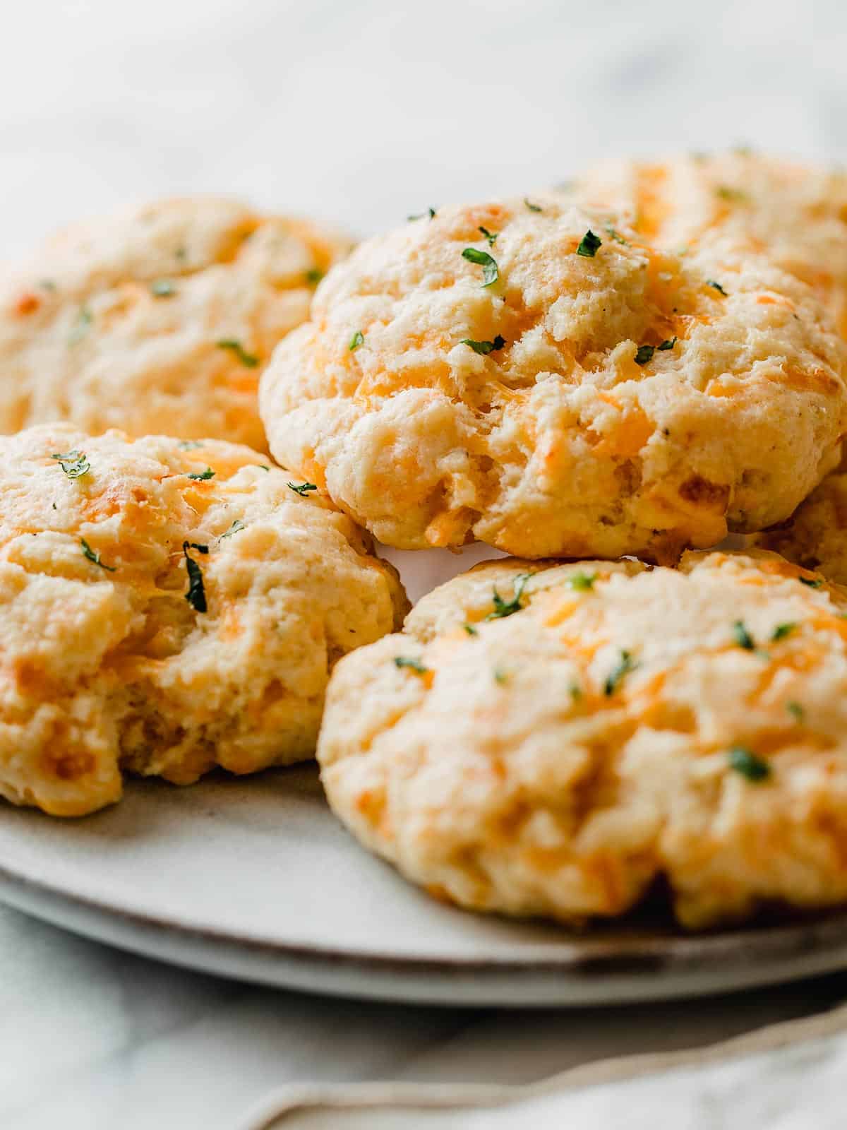Cheddar bay biscuits stacked on a plate.