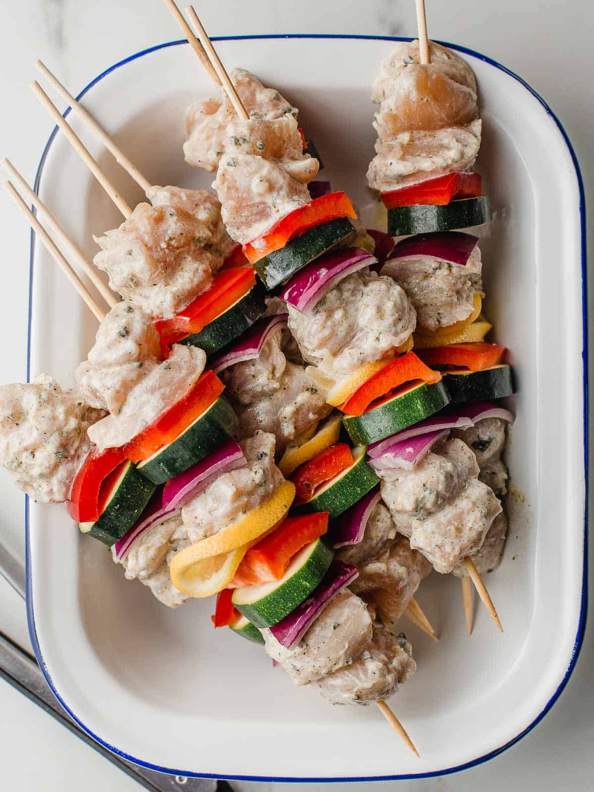 Raw chicken and vegetables on wooden skewers.