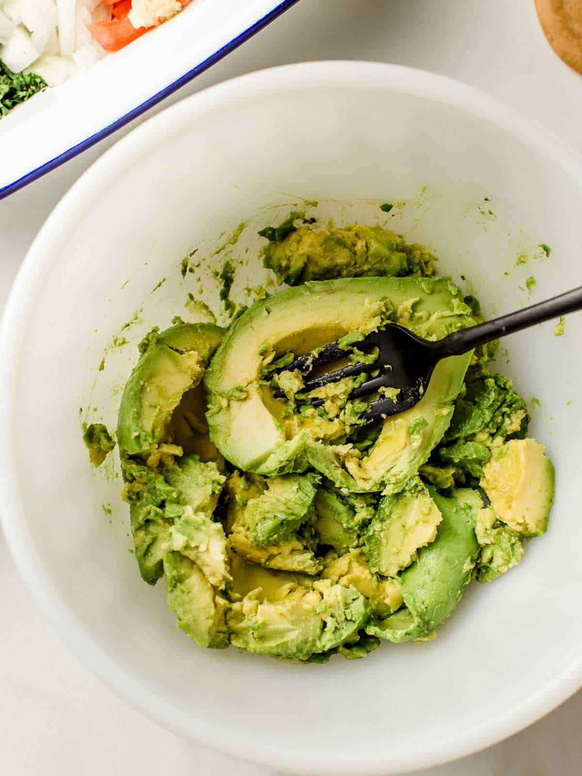 Mashed avocado in a bowl with a fork.