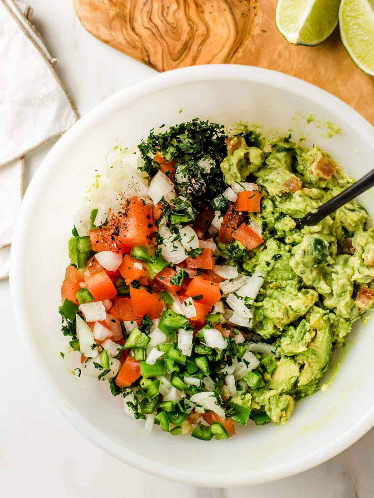 A bowl with all of the guacamole ingredients ready to be mixed.