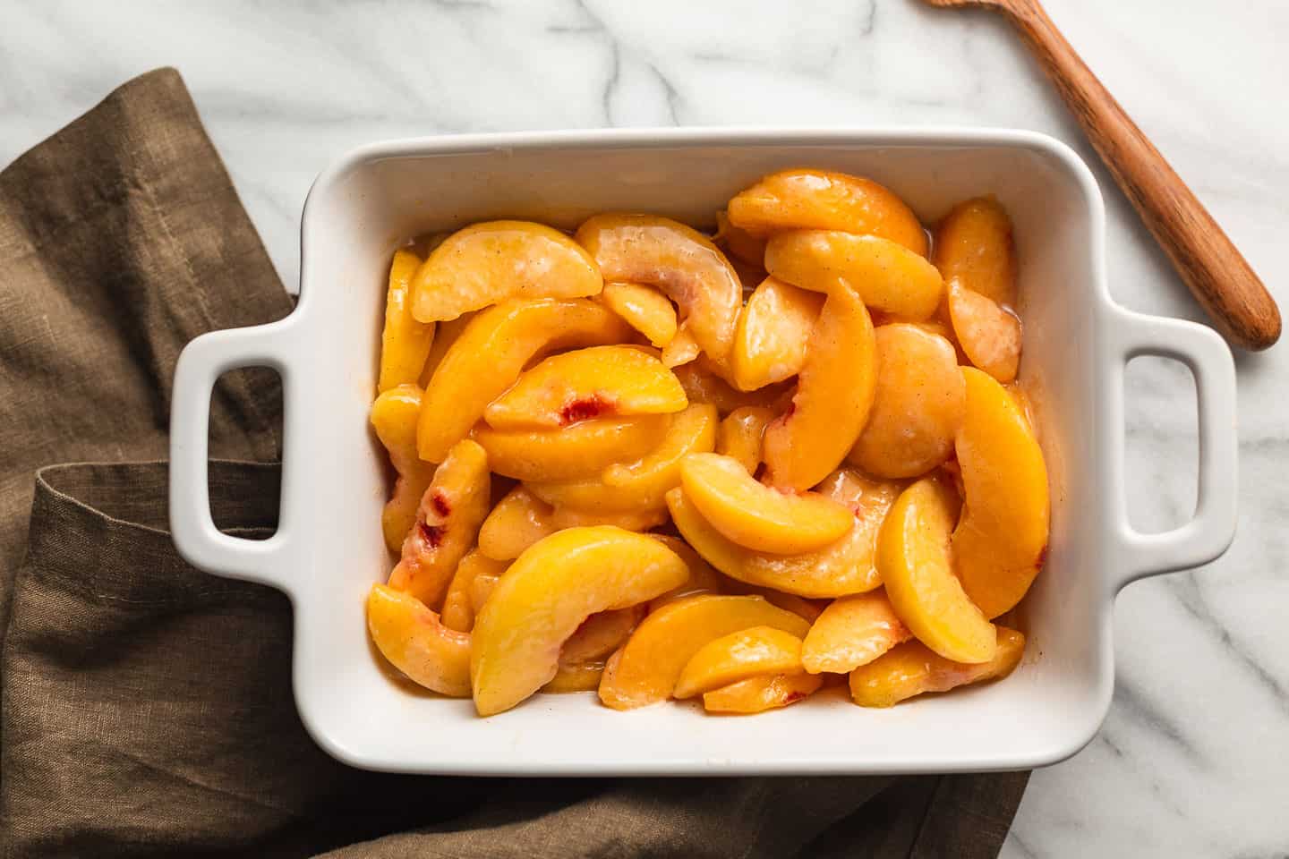 Peach crisp filling in a baking dish.