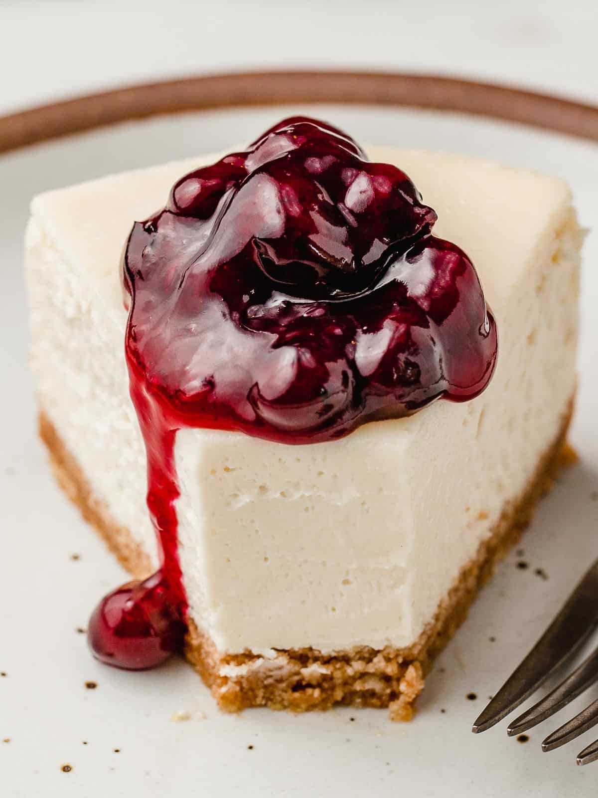 A slice of cheesecake with blueberry topping on a plate.