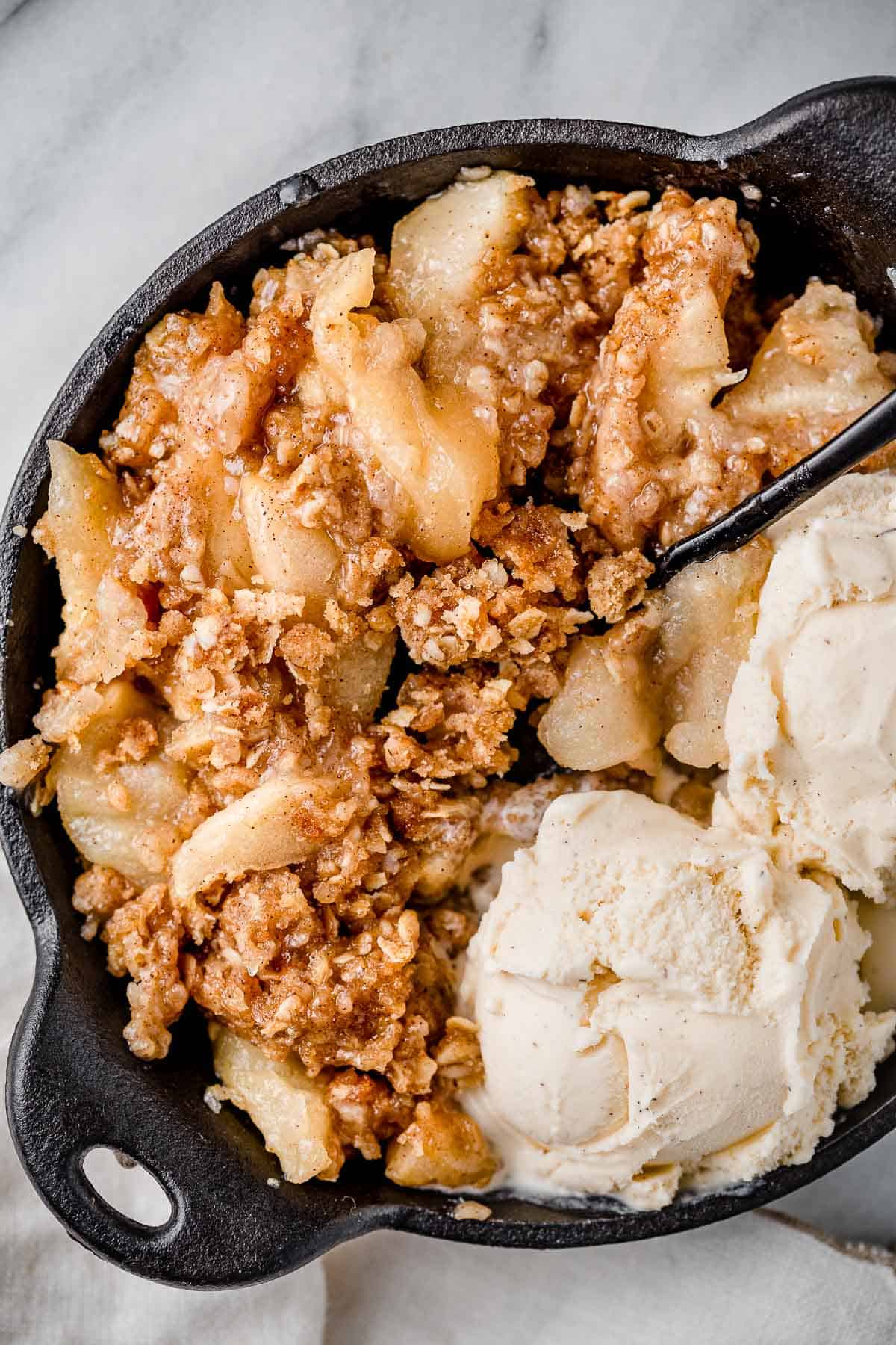 Apple crisp in a bowl with vanilla ice cream.