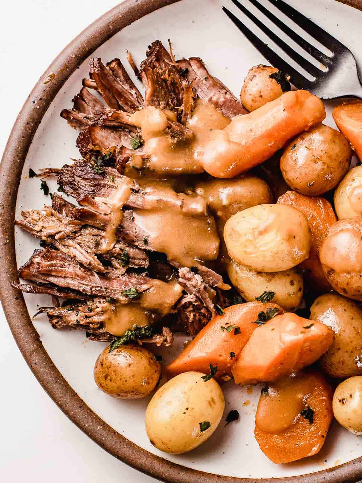 Classic pot roast with gravy on a plate with gravy.