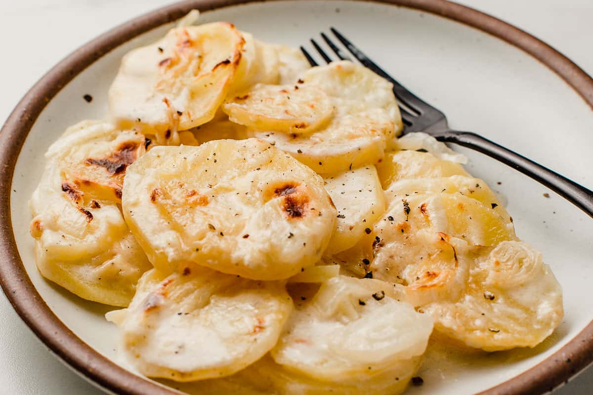 Scalloped potatoes on a plate with a fork.