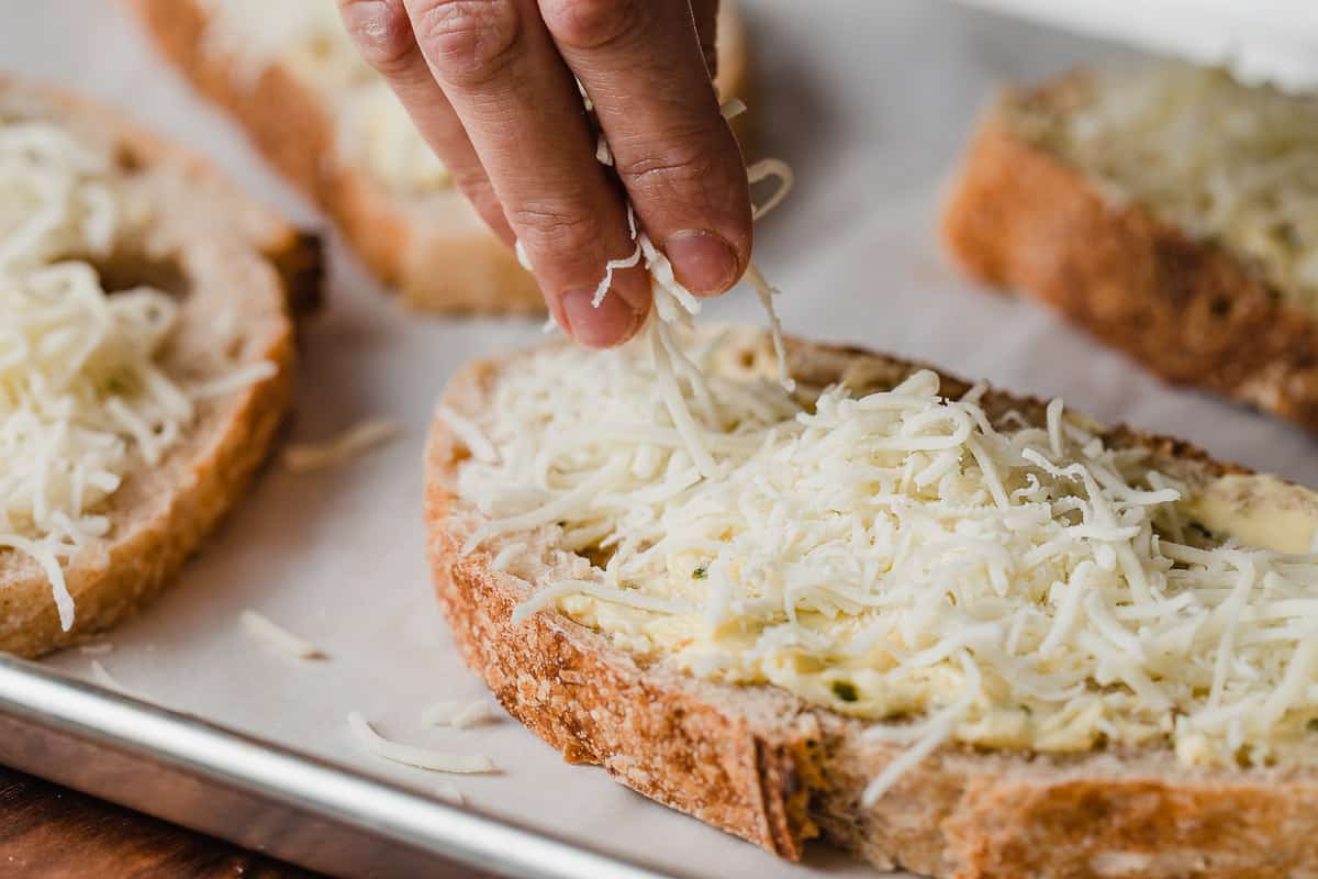 Putting cheese on sourdough garlic bread.