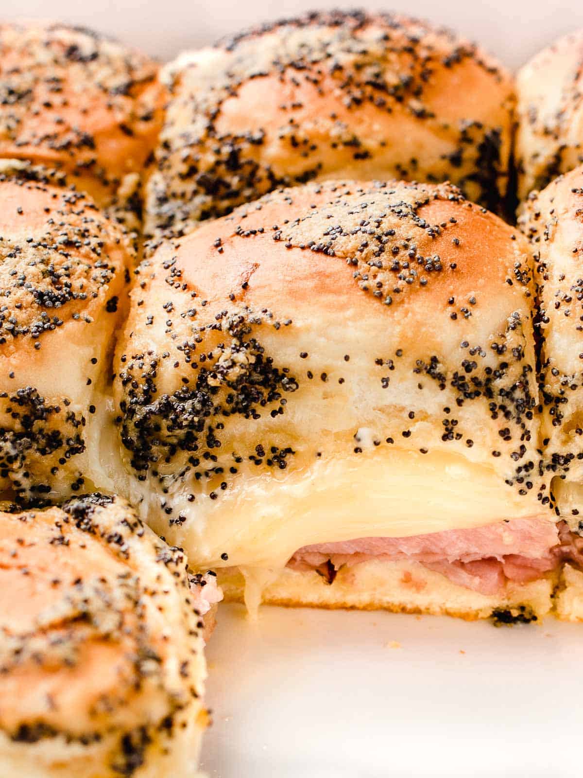 A closeup photo of ham and cheese sliders in a baking dish.