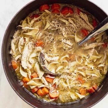 Chicken noodle soup in a dutch oven with a ladle.