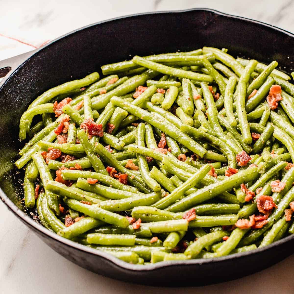 Green beans with bacon in a cast iron skillet.