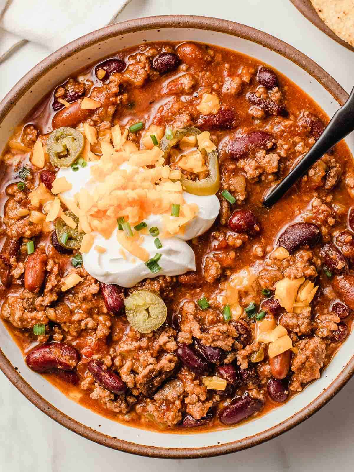 Slow cooker chili in a bowl with toppings.