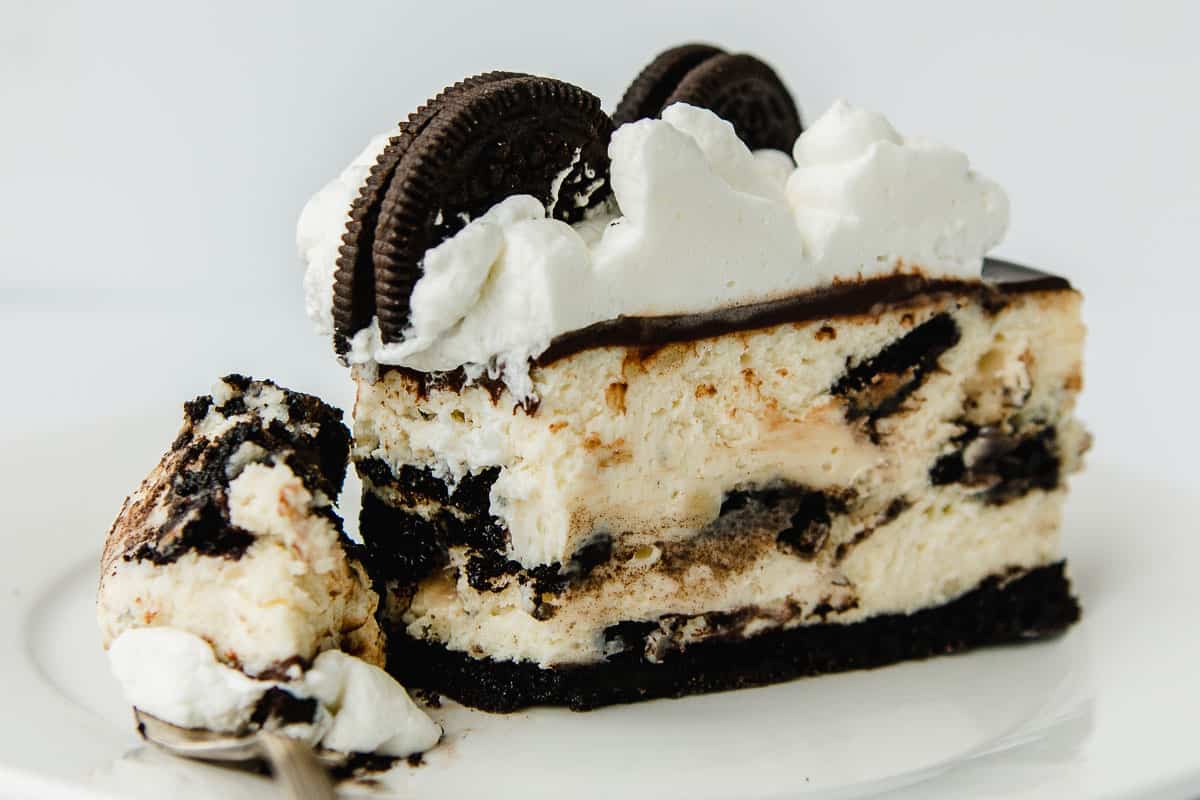 A slice of Oreo Cheesecake on a cake stand.