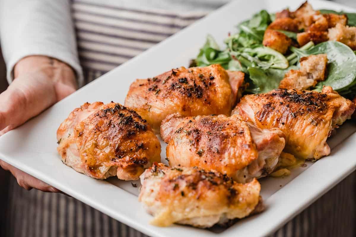 Chicken thighs and salad on a serving platter.