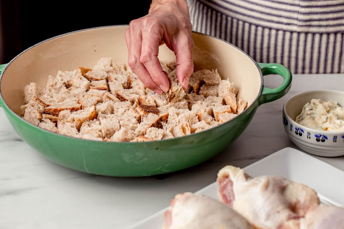 A person placing the croutons in a skillet.