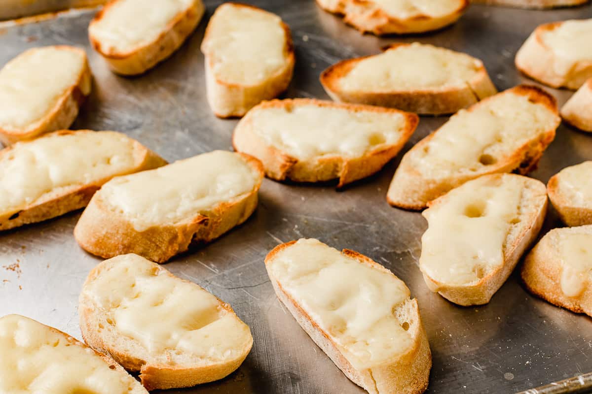 Bread slices with melted cheese on a baking sheet.