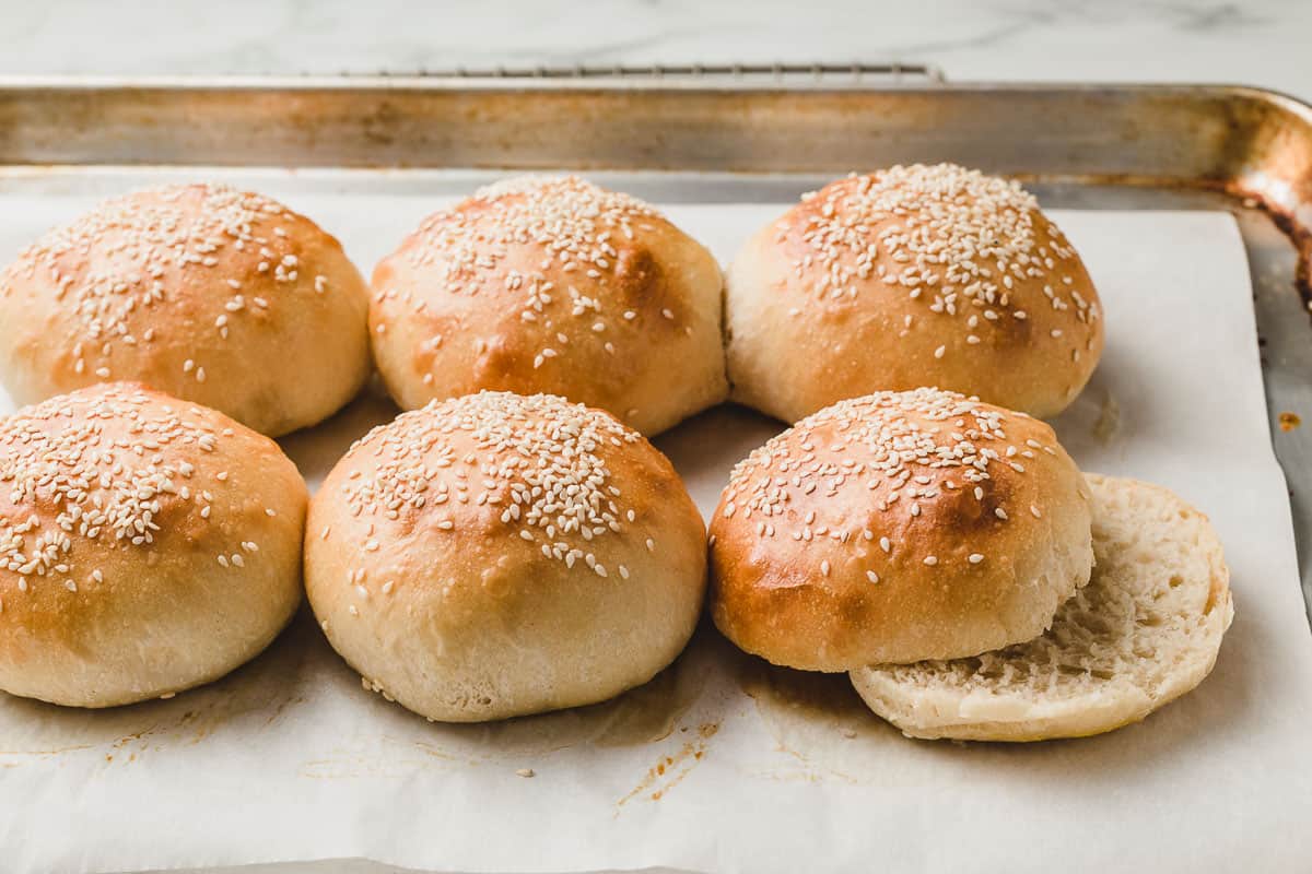Sourdough hamburger buns baked with one cut in half.