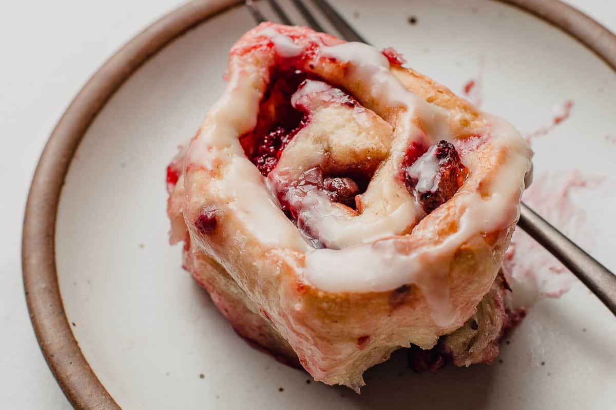 Sourdough berry sweet roll on plate with fork.