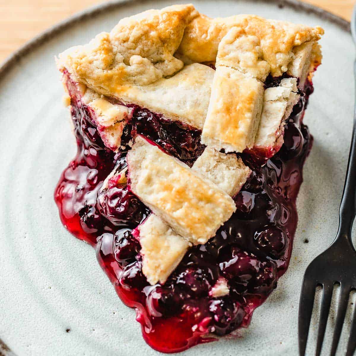 A slice of blueberry pie on a plate.