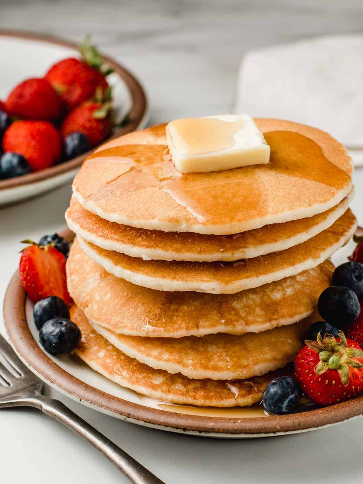 Stack of sourdough pancakes on a plate with berries.