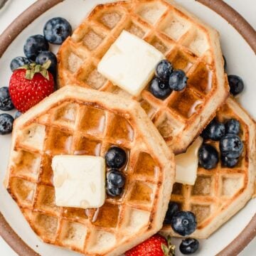 Stack of sourdough waffles on a plate with berries.