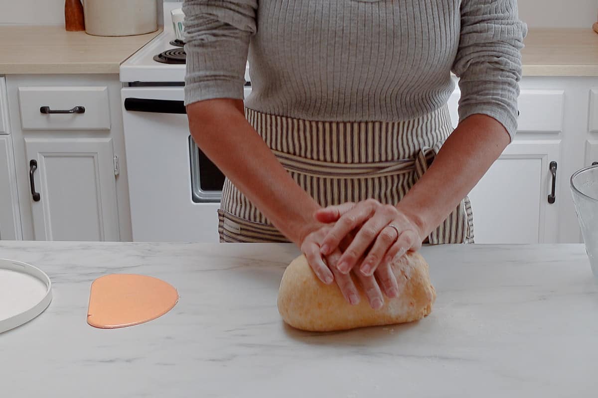 A woman kneading the sourdough sweet potato roll dough.
