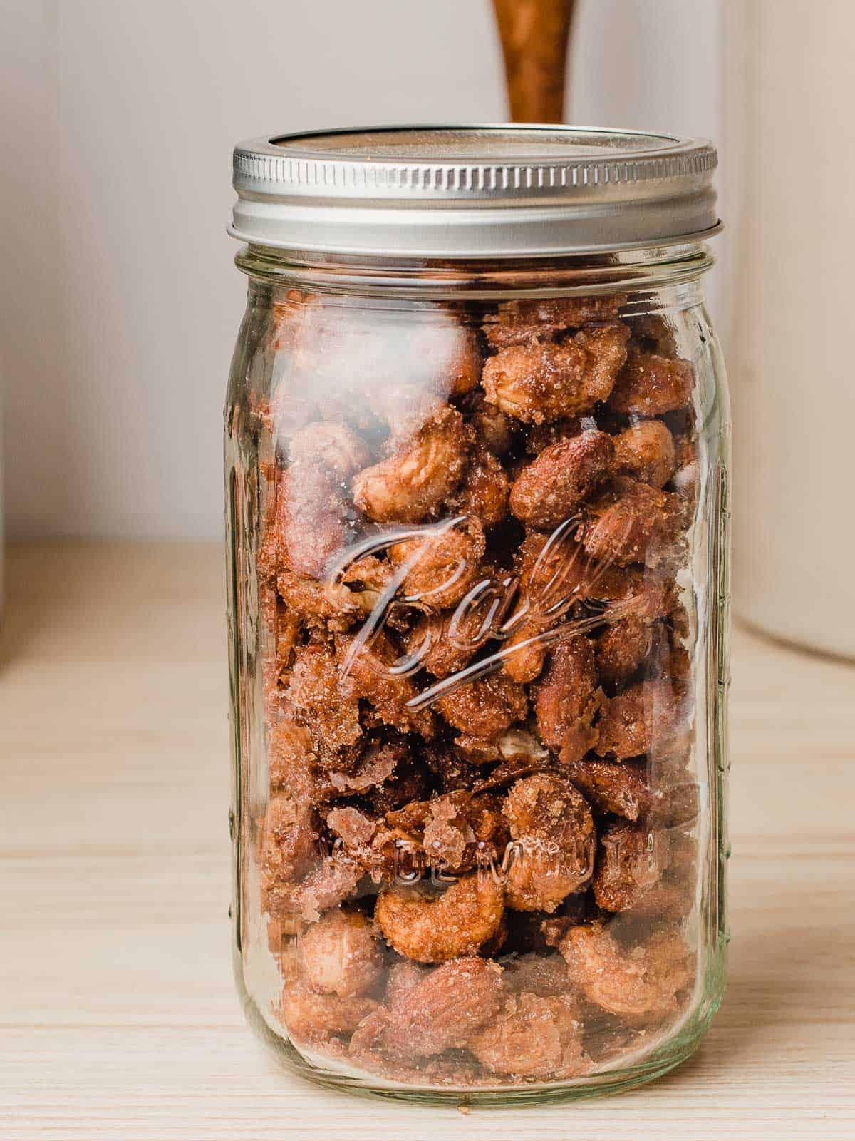 A glass jar filled with candied nuts for storage.