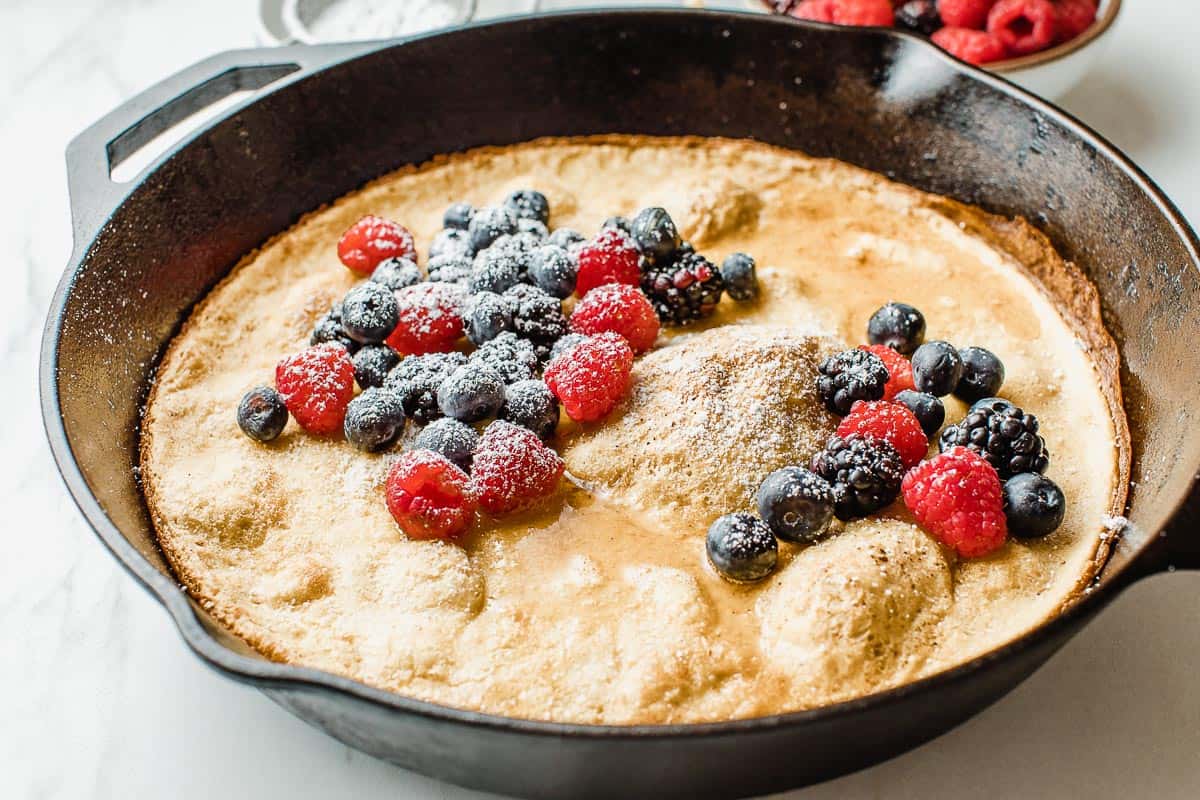 Sourdough dutch baby in a cast iron skillet with berries.
