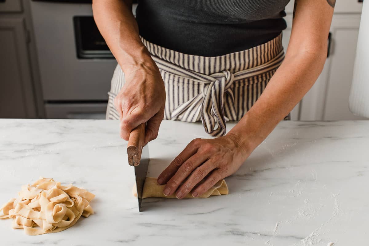 A woman rolling sourdough pasta dough.